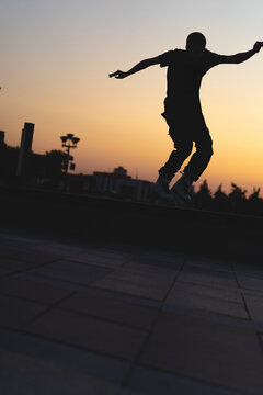 Man performing a trick on roller skates at sunset, urban environment