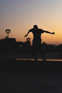 Man performing a trick on roller skates at sunset, urban environment
