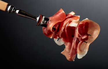 Slices of prosciutto on a fork.