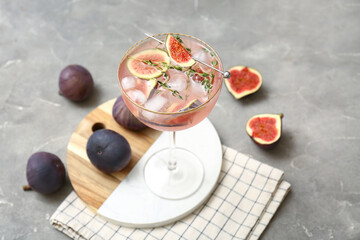 Glass of tasty fig lemonade on grey grunge background, closeup