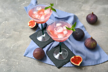Glasses of tasty fig lemonade on grey grunge background, closeup
