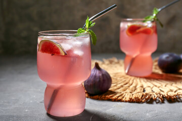 Glass of tasty fig lemonade on grey grunge table, closeup