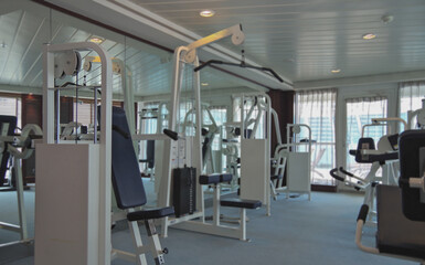 Staying fit with cardio fitness equipment and treadmills in gym or fitness center on cruiseship or cruise ship liner	