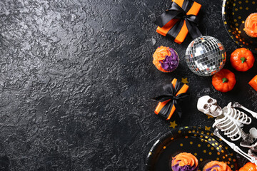 Disco ball with tasty cupcakes, gift boxes, skeleton and Halloween decor on black grunge background