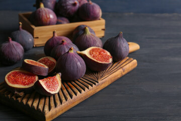 Cutting board with fresh ripe figs on black wooden table