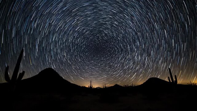 Dazzling star trails arc across the dark night sky above a silhouetted desert landscape in a stunning circular timelapse cosmos, desert, destiny
