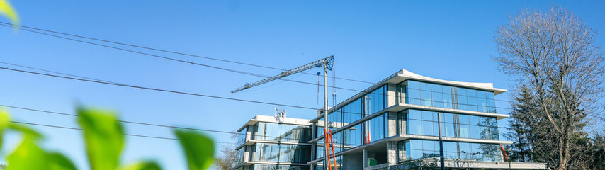 Obraz premium Modern architectural design with a crane against a clear blue sky.