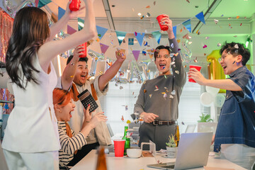 Excited office team celebrates incredible profit growth and victory results announcement together, cheering enthusiastically while monitoring financial performance on screen during triumphant night