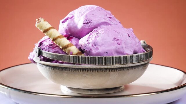 Fruit ice cream balls in a metal bowl slowly rotate against a brightly colored background.