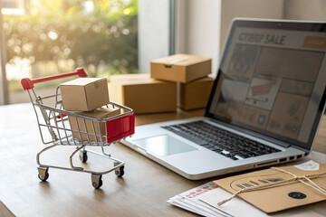 Fototapeta premium Laptop with mini shopping cart and small parcel boxes on table in daylight. Concept for online shopping, e-commerce, Black Friday and Cyber Monday sale.