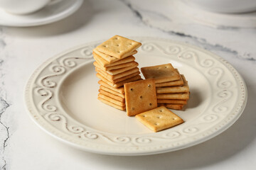 Composition with plate of tasty crackers on marble background, closeup