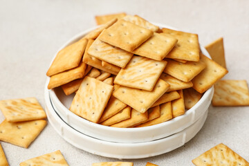 Composition with plate of tasty crackers on beige grunge background, closeup