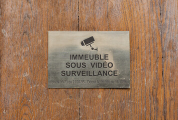 Immeuble avec panneau de surveillance vidéo sur une porte en bois.