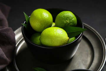 Bowl with fresh ripe limes on black background, closeup