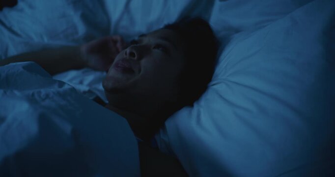 Young Asian Woman Lies Awake at Night, Unable to Sleep. Girl Shifts Uncomfortably, Overwhelmed by Stress and Anxious Thoughts. Concept of Insomnia, Restless Dreams, Mental Tension, Poor Rest.