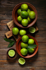 Bowls with fresh ripe limes on wooden background