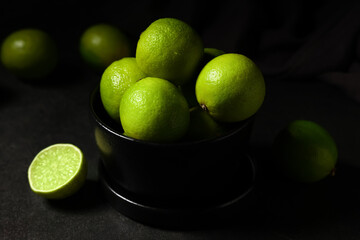 Bowl with fresh ripe limes on black background, closeup