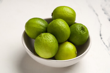 Bowl with fresh ripe limes on white background, closeup
