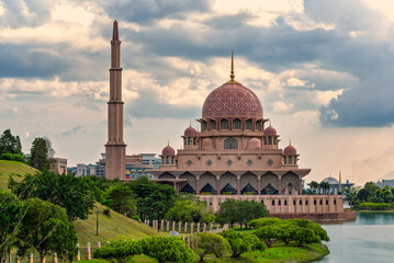 Putra Mosque, with its distinctive pink dome and minaret, stands majestically by Putrajaya Lake in Putrajaya, Malaysia, under a dramatic cloudy sky. © Khaled El-Adawi