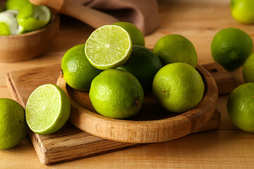 Plate with fresh ripe limes on wooden background, closeup
