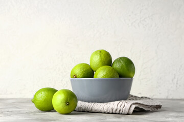 Bowl with fresh ripe limes on grey table