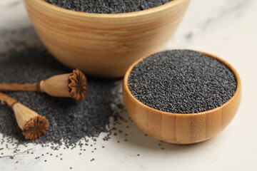 Wooden bowls with poppy seeds on white background, closeup