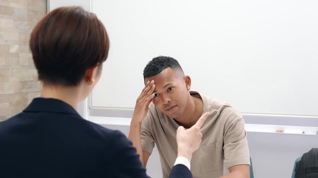 悩む黒人男性と面談する日本人女性スタッフ