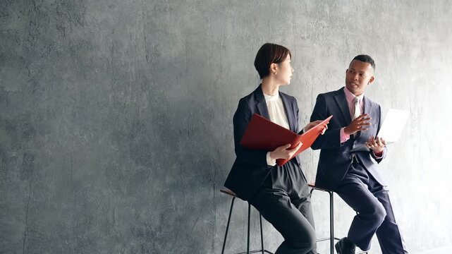 A black male businessman and a Japanese female staff member having a conversation in a stylish room