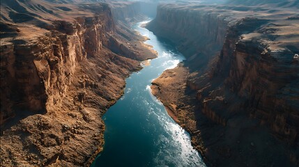 A dramatic aerial view of a river snaking through a deep canyon with vibrant textures on the cliffs