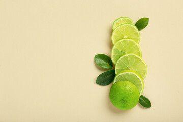 Slices of fresh ripe lime and leaves on beige background