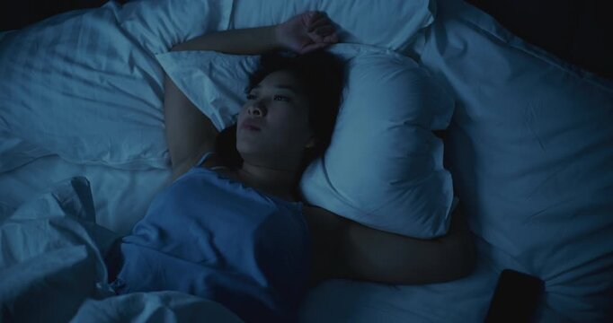 Asian Girl Suffering From Insomnia, Upset and Restless in Bed. She Tosses, Turns, and Struggles to Fall Asleep, Face Showing Stress, Anxiety, and Exhaustion. Concept of Poor Rest, Tension, Insomnia.