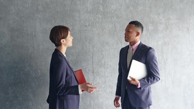 A black male businessman and a Japanese female staff member having a conversation in a stylish room