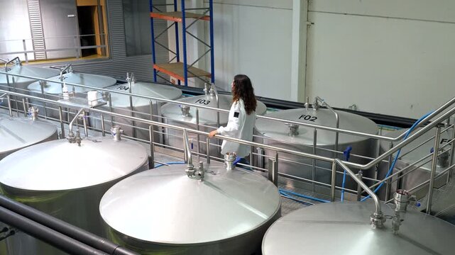 Female brewery worker inspecting fermentation tanks
