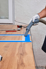 Worker man vacuums new kitchen after cutting hole for the sink in the kitchen countertops