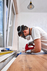 repairman using electric handheld jigsaw and cutting hole for the sink in the kitchen countertops