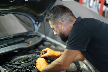Car mechanic examining engine during vehicle maintenance service