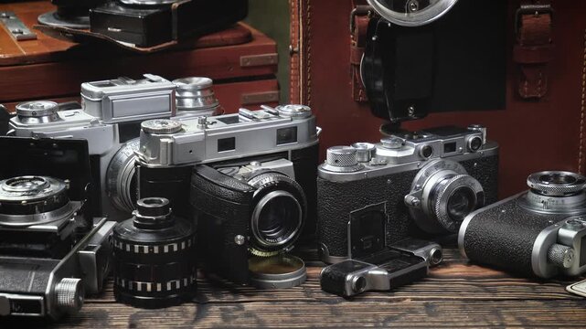 Old cameras in a composition on a wooden background, slowly moving in a horizontal plane.