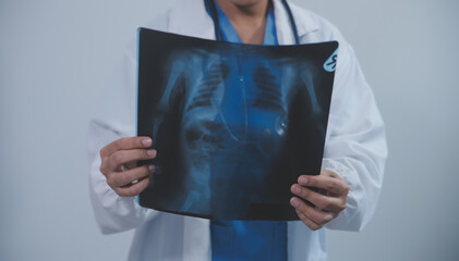 Asian Muslim doctor in hijab and scrubs headphones around her neck Stand confidently in the medical office, isolated on white background, holding x-ray film.