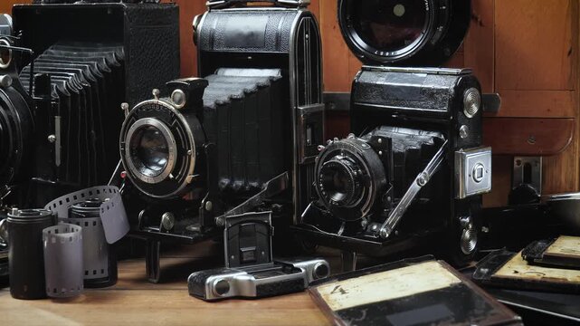 Old cameras in a composition on a wooden background, slowly moving in a horizontal plane.