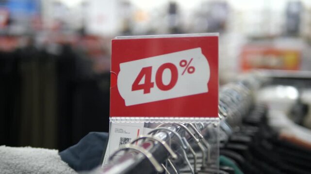 A bright red 40 percent off discount sign prominently displayed on a clothing store rack. This clear retail marker is perfect for advertising sales events, shopping promotions, and fashion discount
