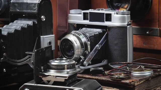 Old cameras in a composition on a wooden background, slowly moving in a horizontal plane.