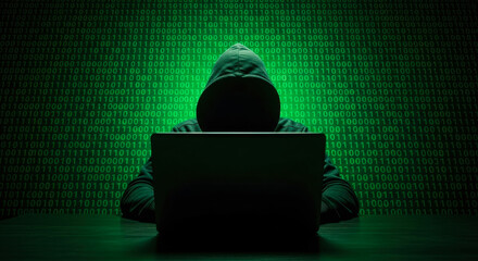 Hooded figure typing on laptop against green binary code background hacker anonymous