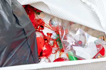 Jumble of Christmas decorations, nestled within storage container, awaiting their next festive season. Red ornaments, silver baubles, and twinkling tinsel, all crammed together in a box