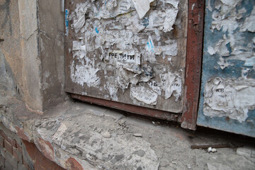 A dirty notice board filled with paper notices. Paper ads on a shabby wall. Rental, sale, help offers.