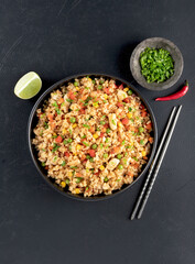 Fried rice with chicken,vegetables:carrots,peppers,corn and green peas on black background. Top view