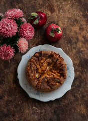 Apple cake with cinnamon, bouquet of asters, apples on a wooden table, top view