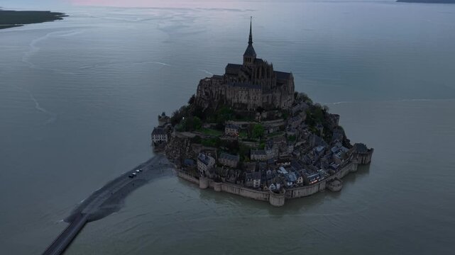 Aerial view of Mont Saint-Michel Abbey standing proudly on a rocky tidal island, connected by a causeway amid the serene waters, Mont Saint-Michel, Normandy, France.