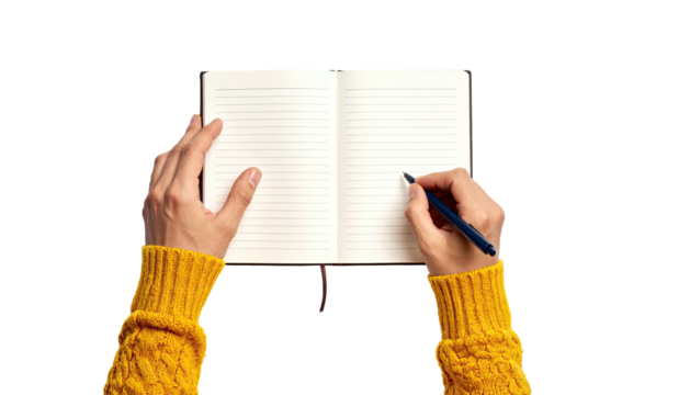 Person writing in an open notebook, hands visible, wearing a yellow sweater