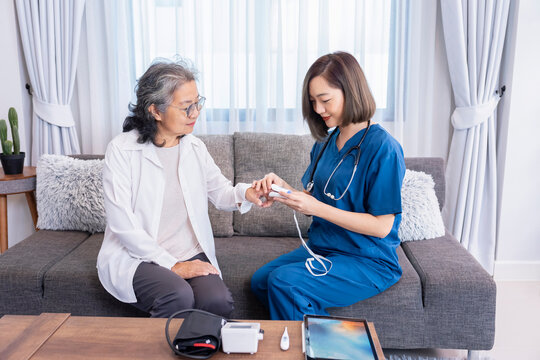 asian female visiting nurse measuring pulse oximeter senior woman patient at home,health care worker physical examine elderly woman,home nursing care,home health care