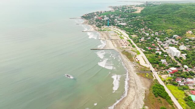 traveling aerial drone view of the puerto colombia coastline with waves breaking on the sandy beach